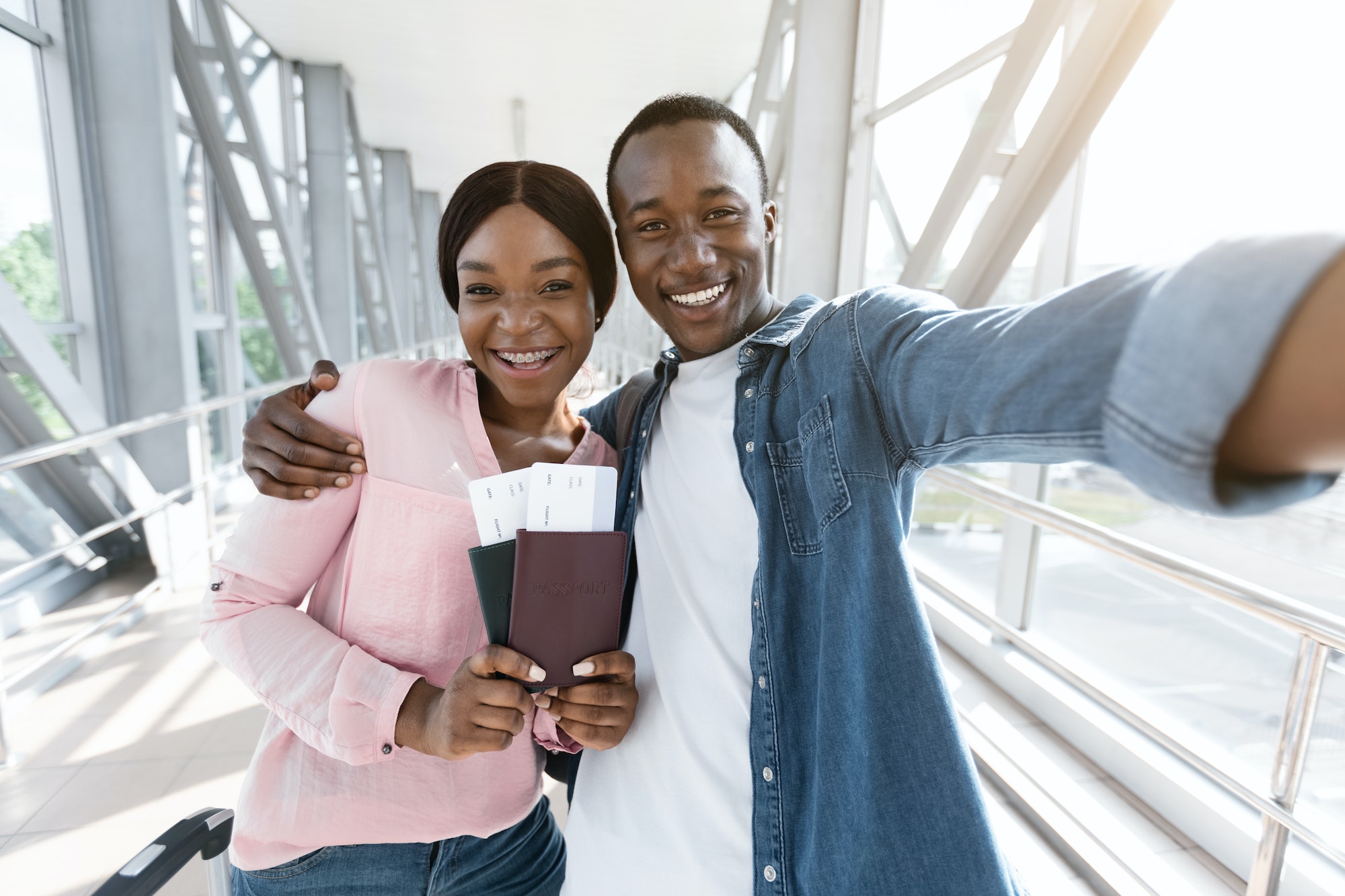 Traveling Together. Happy african couple taking selfie in airport, waiting for boarding